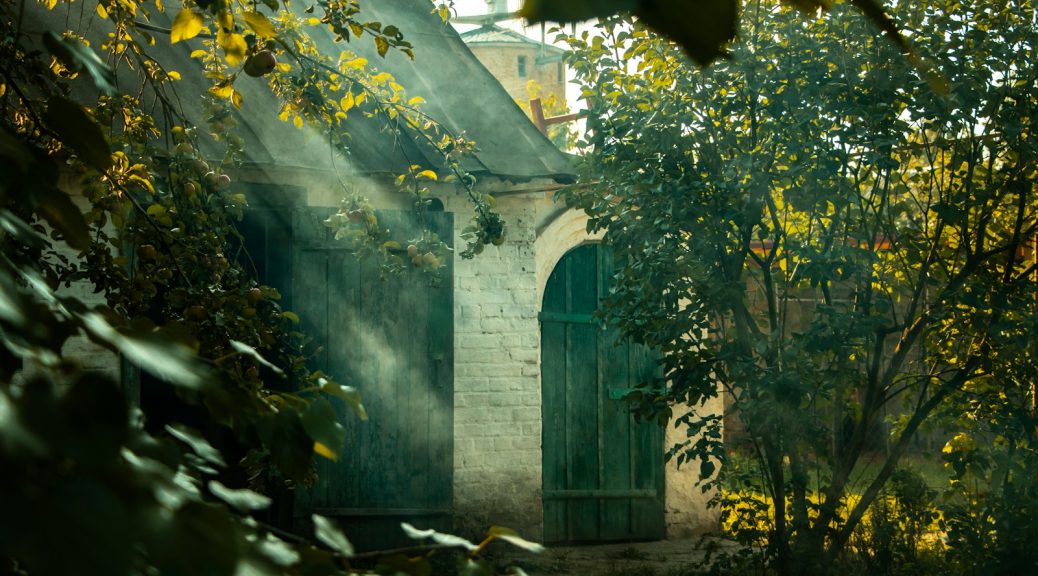 a stone building with a door and trees around it