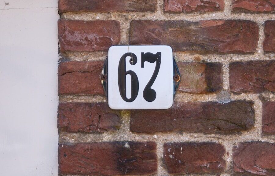 A house number, "67," is seen on a brick wall.